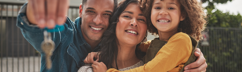 A family smiling because they've collected the keys to their new home on completion day